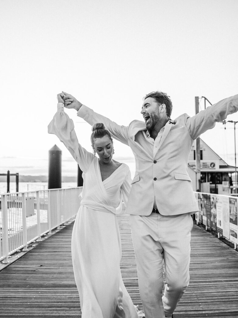 Northland Wedding, The Duke Russell Bride and groom walking along the waterfront in Russell